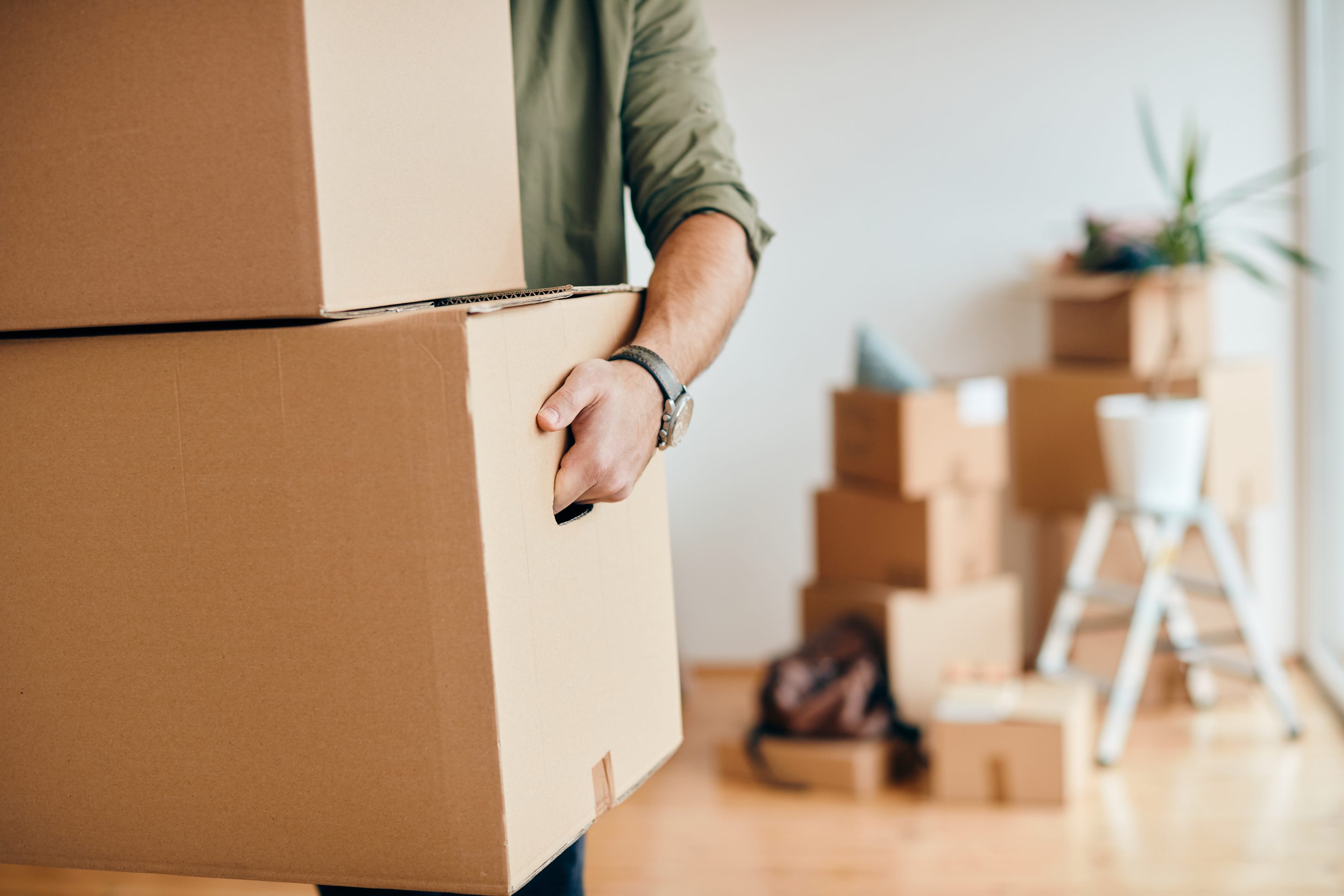 Close-up of man carrying cardboard boxes while relocating into n